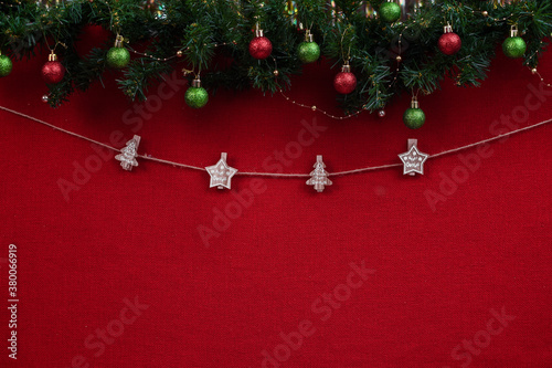 Christmas clothespins on a rope and a place for an inscription on a red fabric background with Christmas tree branches and balls