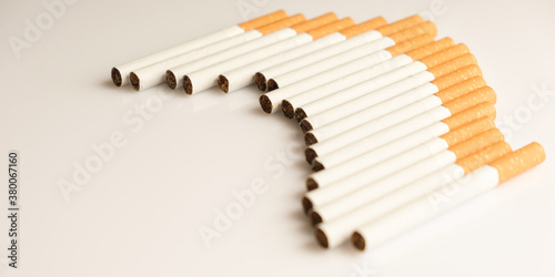 Cigarettes with a yellow filter lie on a white surface