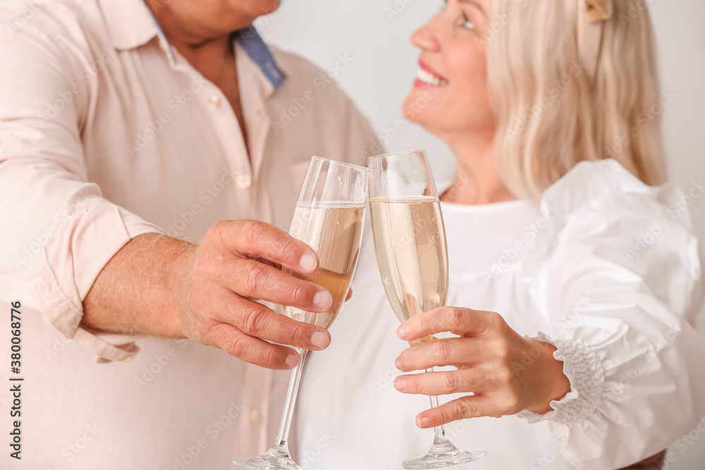 Elderly couple with champagne celebrating New Year on light background Elderly couple with champagne celebrating New Year on light background
