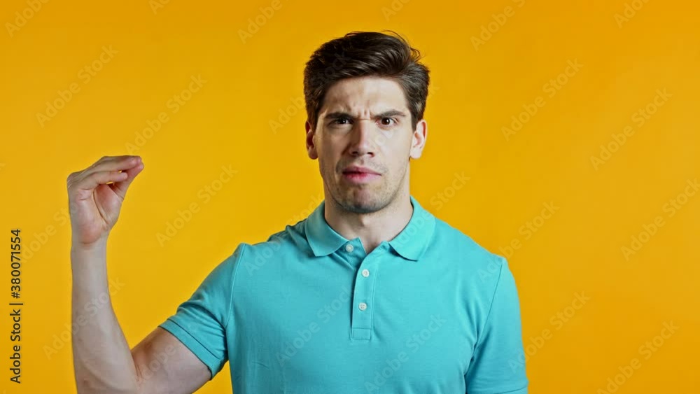 Handsome bored man showing bla-bla-bla gesture with hands and rolling eyes isolated on yellow background. Empty promises, blah concept. Lier. Handsome bored man showing bla-bla-bla gesture with hands and rolling eyes isolated on yellow background. Empty promises, blah concept. Lier.