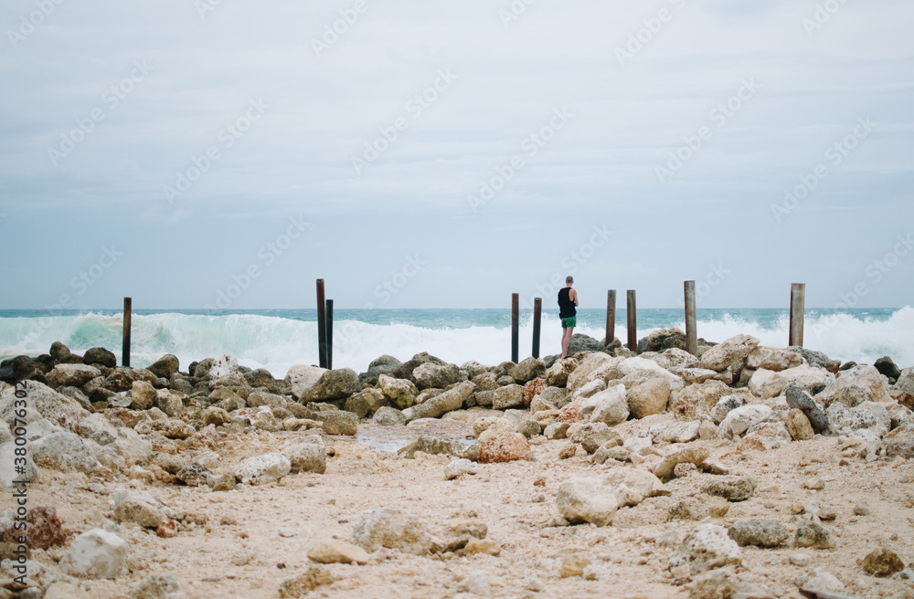 Young man stands in front of the ocean Young man stands in front of the ocean