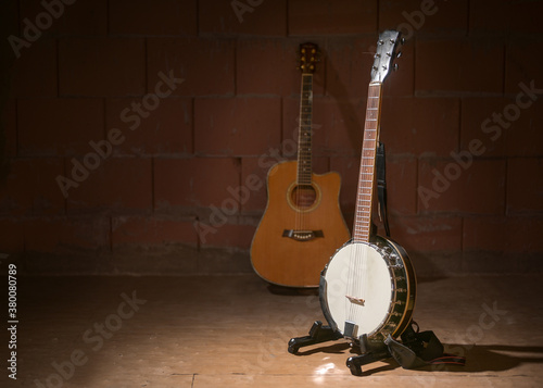 Banjo and a blurry guitar in the background against a dark brick wall in the garage of a music band, copy space photo