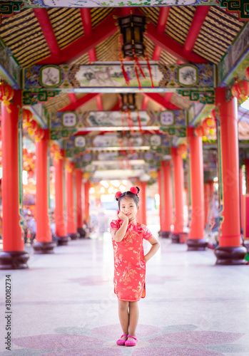 cute little asian girl in chinese traditional dress smiling and standing in the temple.Happy chinese new year concept.