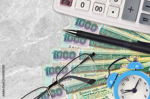 1000 Sri Lankan rupees bills and calculator with glasses and pen. Business loan or tax payment season concept. Time to pay taxes photo