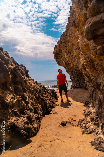 A young man enjoying the beautiful rocks on the shoreline at Cala de la Media Luna in Cabo de Gata Natural Park, Nijar, Andalucia. Spain, Mediterranean Sea