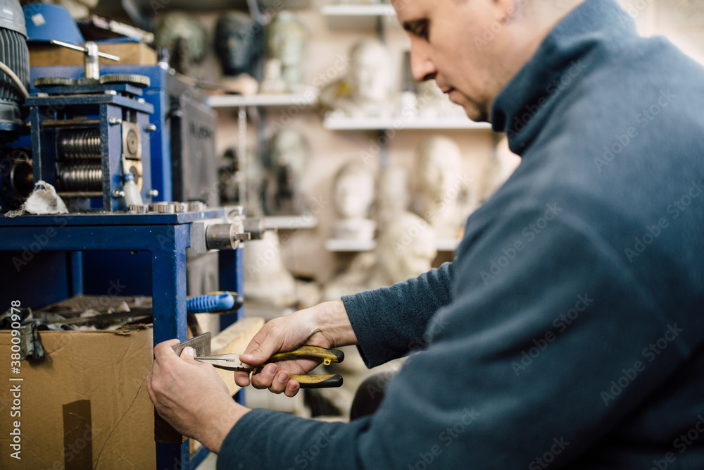 Man thinning out wire with pliers Man thinning out wire with pliers