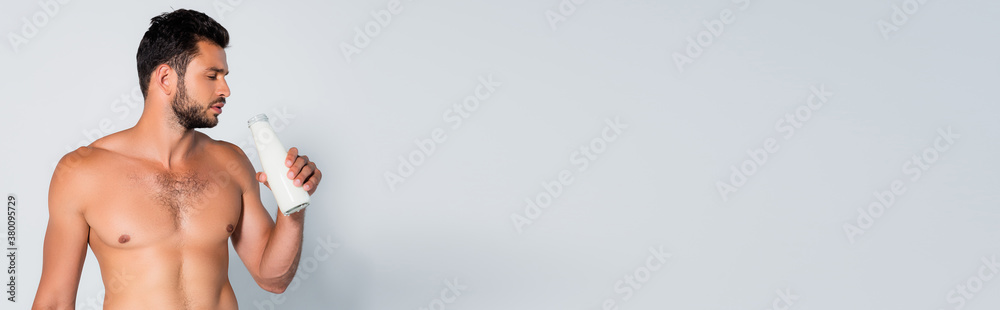 panoramic crop of shirtless and bearded man holding bottle with fresh milk on grey panoramic crop of shirtless and bearded man holding bottle with fresh milk on grey