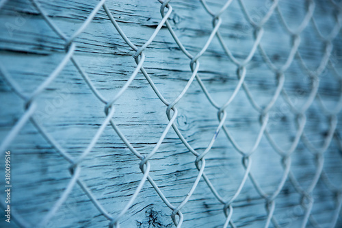 Blue wire mesh fence over blue wooden wall