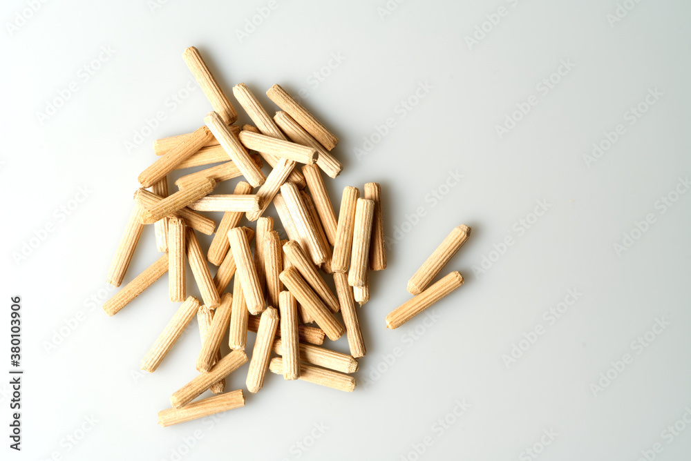 pile of wooden dowels on white table, carpentry connectors, top view pile of wooden dowels on white table, carpentry connectors, top view