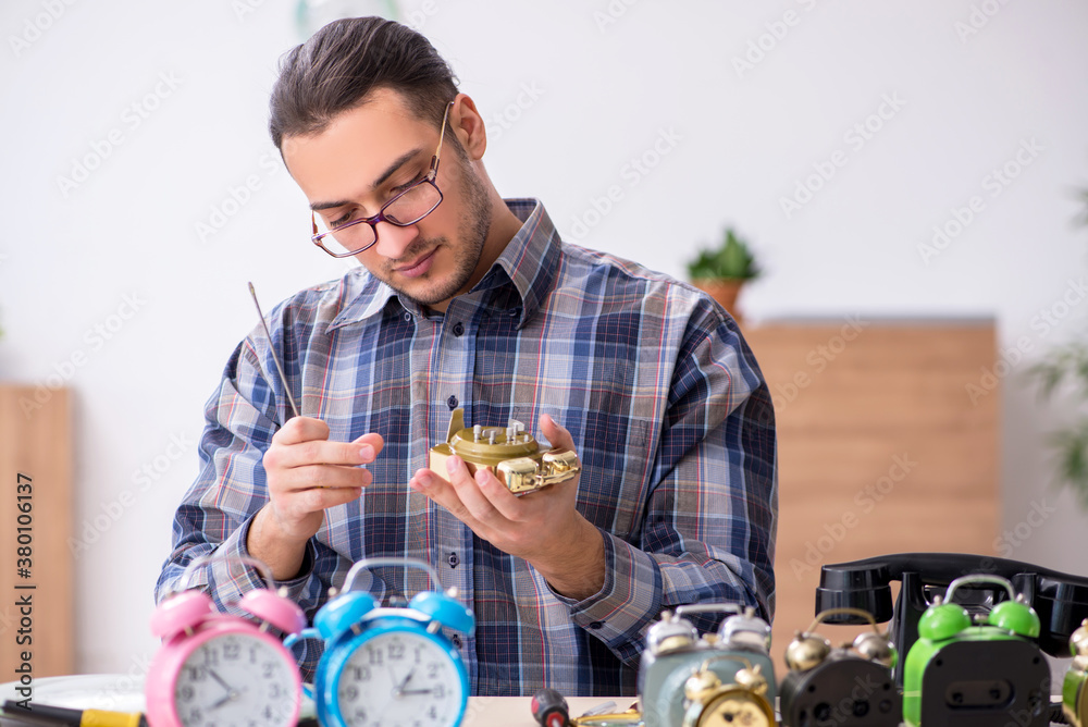 Young male watchmaker working in the workshop Young male watchmaker working in the workshop