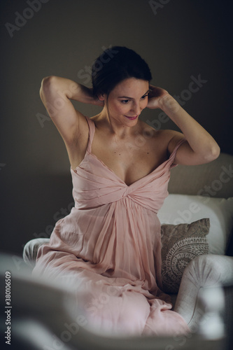 Beautiful woman putting in order her chignon while sitting on armchair