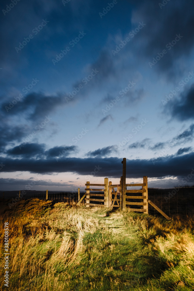 Gate and signpost lit by car headlights at twilight. Derbyshire, Gate and signpost lit by car headlights at twilight. Derbyshire,