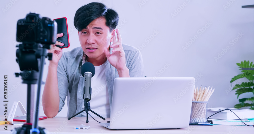 Young asian man selling digital gadgets on social media by streaming live from his home. Young asian man selling digital gadgets on social media by streaming live from his home.