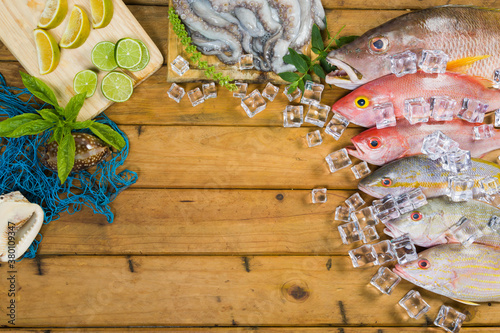 Foto Close-up of a variety of tropical fishes and octopus with ice cube on a wooden table