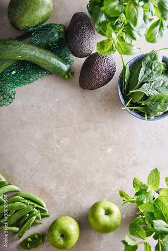 An arrangement of fresh green fruit,vegetables and herbs on a table.