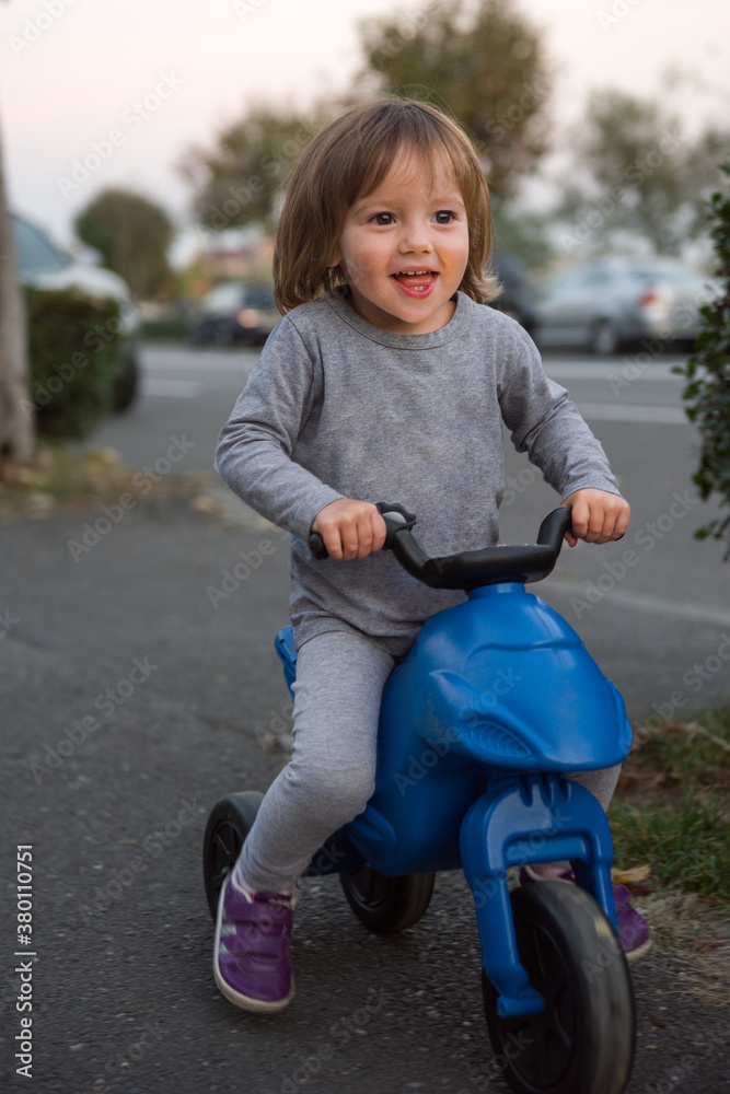 Pretty girl riding blue scooter on the sidewalk Pretty girl riding blue scooter on the sidewalk