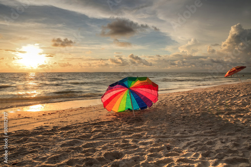 Rainbow umbrella on White sand at Delnor Wiggins State Park at sunset photo