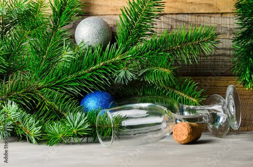 Spruce branches with green needles and Christmas balls on a wooden background. Two empty glasses.