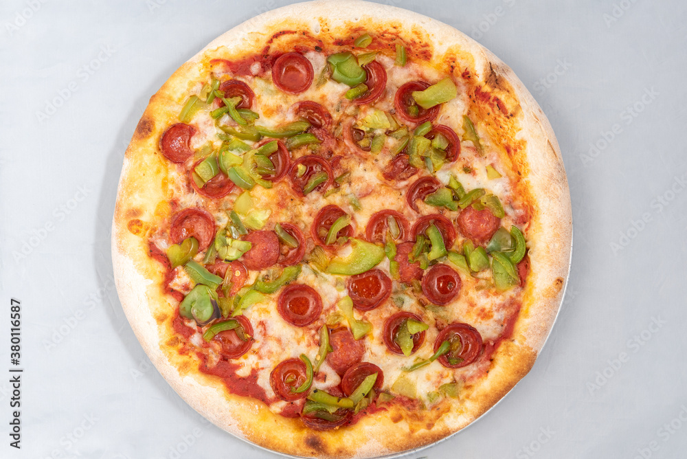 Overhead view of healthy sized pepperoni and green pepper pizza with thick crust to complete a delicious meal to eat