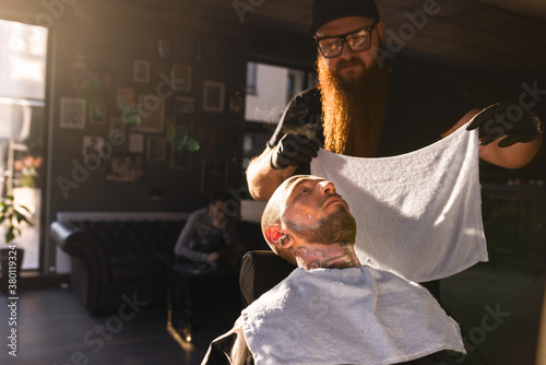 Hairstylist holding white towel preapring to shave his customer