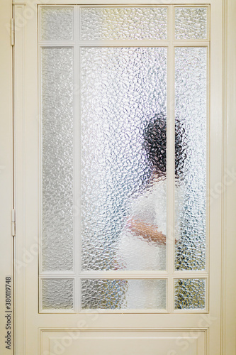 Pregnant woman silhouette behind glass door photo