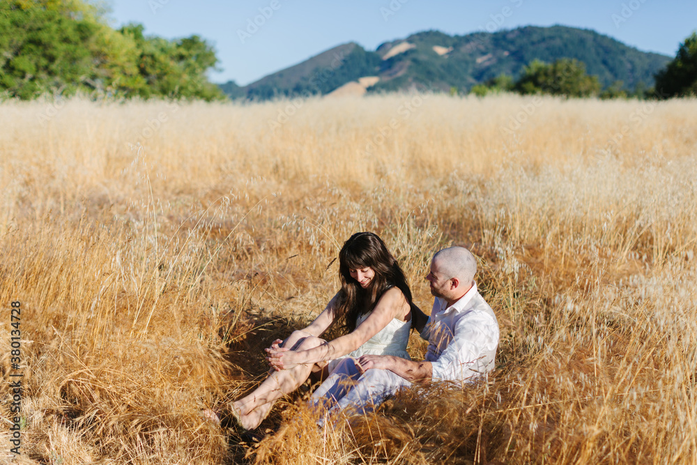 Wedding Couple Sitting in Golden Grass at Sunrise Wedding Couple Sitting in Golden Grass at Sunrise