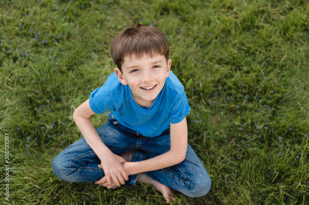 Adorable tween boy resting on a lawn covered with blue flowers Adorable tween boy resting on a lawn covered with blue flowers