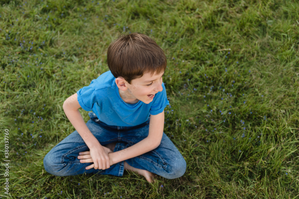 Adorable tween boy resting on a lawn covered with blue flowers Adorable tween boy resting on a lawn covered with blue flowers