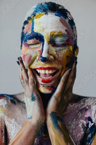 Closeup portrait of laughing young woman with closed eyes and colorful bodyart photo