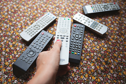 Collection of old television, dvd, video remote controls on flower table cloth photo