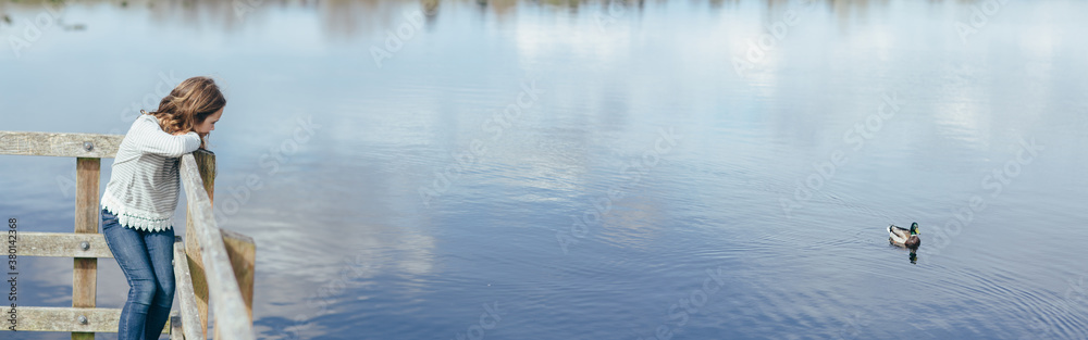 Young girl watching mallard duck on lake Young girl watching mallard duck on lake