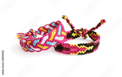 Selective focus of two tied woven friendship bracelets with bright pink pattern handmade of thread isolated on white background