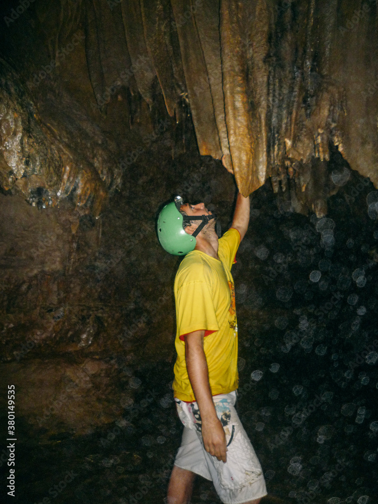 Young adventurer man doing speleology on a cave looking stalactite Young adventurer man doing speleology on a cave looking stalactite