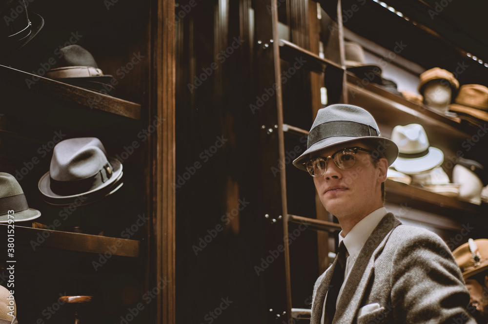 A dapper young man in a suit and tie tries on hats A dapper young man in a suit and tie tries on hats