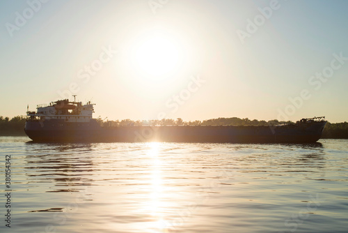 Large cargo ship sailing in still water. Cargo ship sailing against sunset . Cargo ship on the river