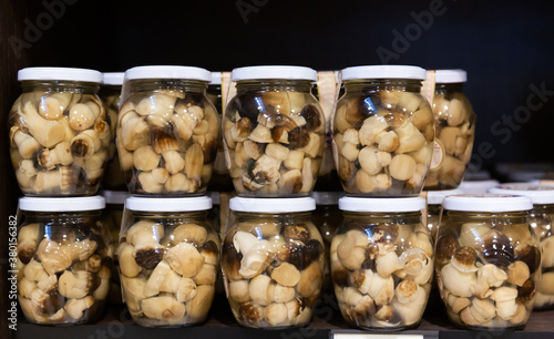 Popular in Catalonia snack of pickled fredolics mushrooms (tricholoma terreum) in glass jars on counter in store photo