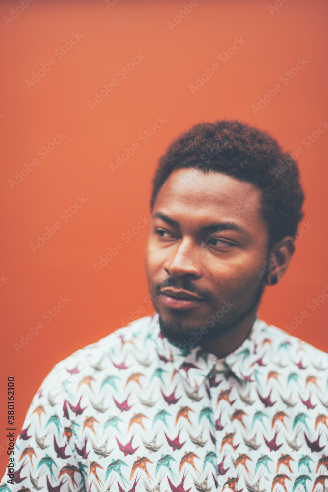 Portrait of modern young black man in front a orange wall. Portrait of modern young black man in front a orange wall.