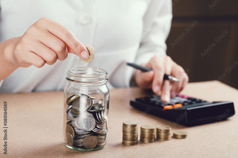 Women putting coin in glass bottle saving bank and account for his money all in finance accounting concept. Women putting coin in glass bottle saving bank and account for his money all in finance accounting concept.