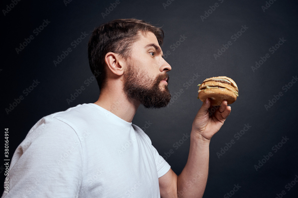 Man eating hamburger fast food restaurant Gourmet eating dark background Man eating hamburger fast food restaurant Gourmet eating dark background