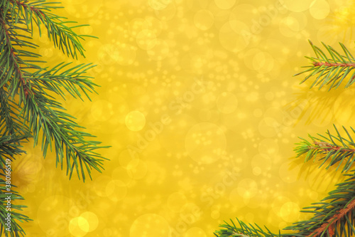 christmas tree branches on yellow festive background bokeh lights, copy space 