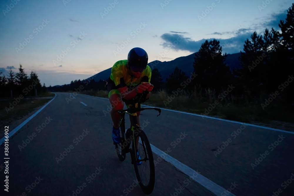 Obraz premium triathlon athlete riding bike at night