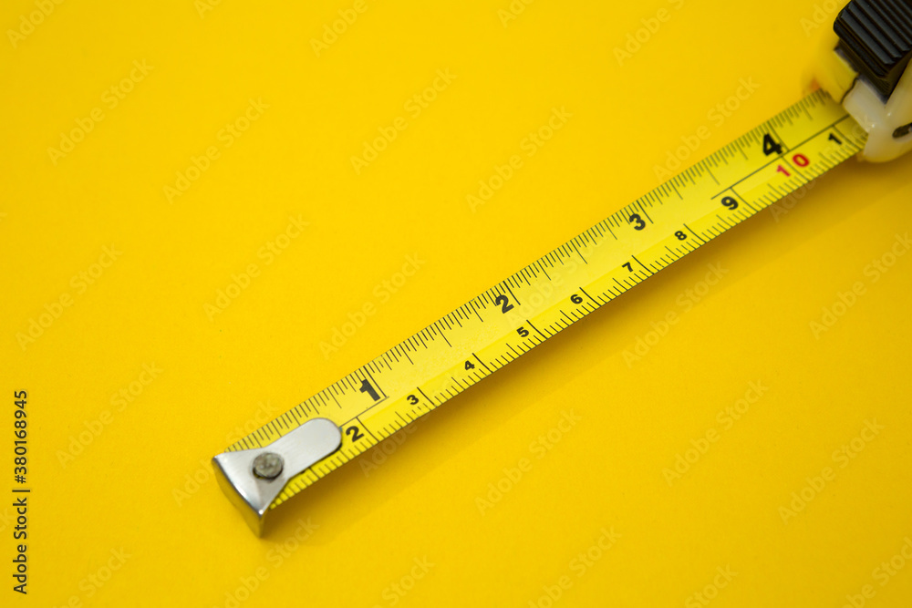 Yellow tape measure on yellow background  and copy space
