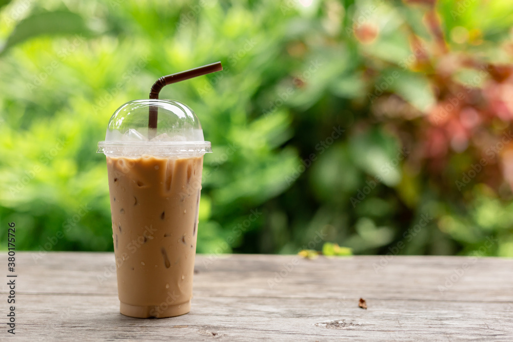 Iced coffee on wooden table and blurred green nature background Iced coffee on wooden table and blurred green nature background