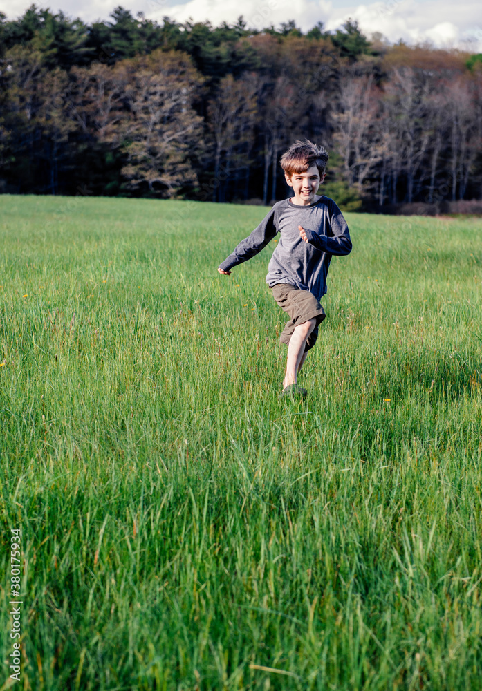 Happy boy runs through a field in springtime Happy boy runs through a field in springtime