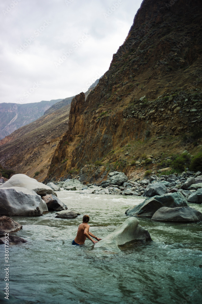 Man crossing a river in a canyon Man crossing a river in a canyon