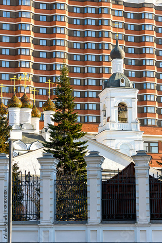 Old white Church on the background of a modern building. A combination of history and modernity.