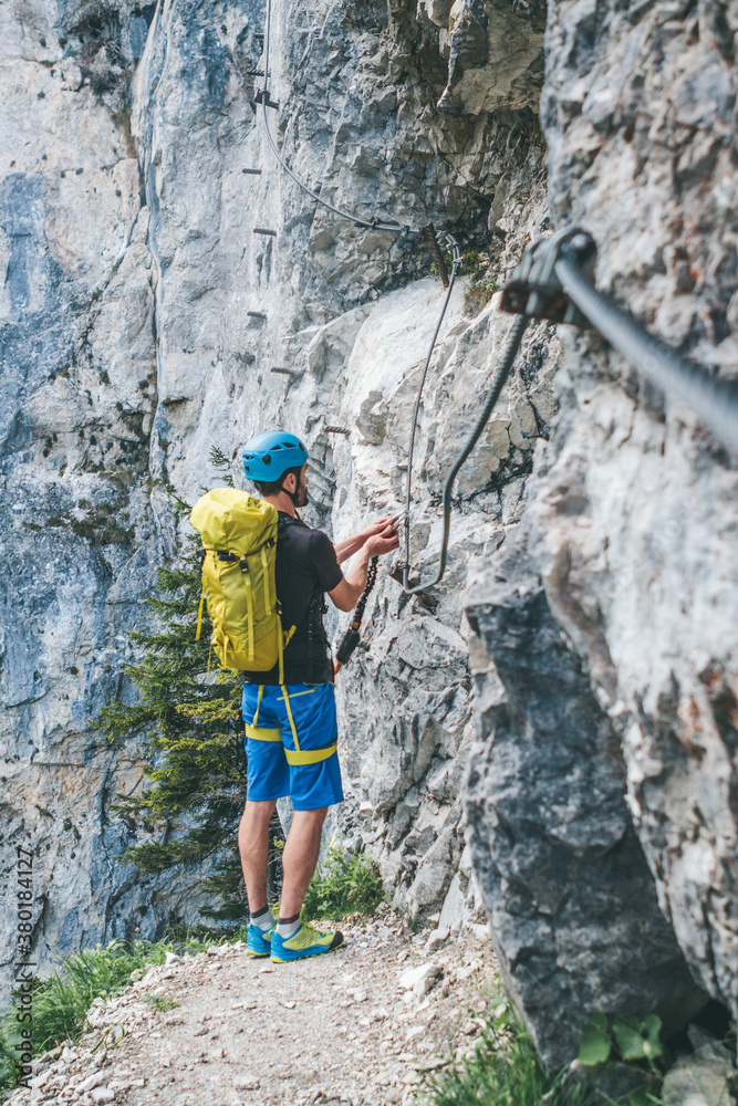 young male climber climbing a via ferrata young male climber climbing a via ferrata