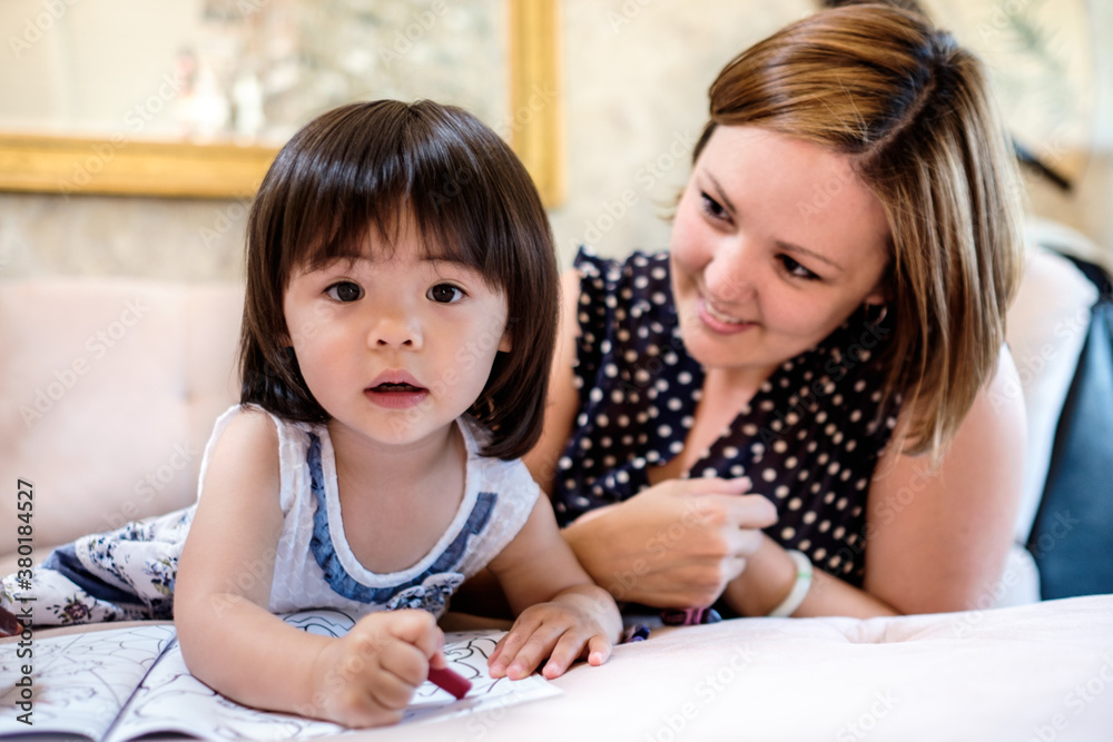Little Asian girl coloring a book with her mom Little Asian girl coloring a book with her mom