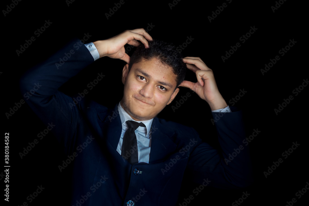 Frustrated man holding his head with tension and posing on a black colored background wearing a blue colored suit. Frustrated man holding his head with tension and posing on a black colored background wearing a blue colored suit.