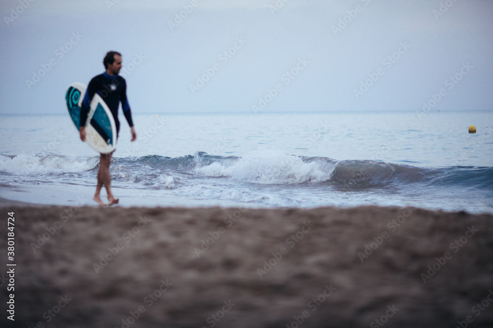 Surfer walking by the ocean at the evening Surfer walking by the ocean at the evening